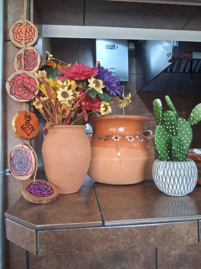 Clay pots with flowers, a painted cactus and hand-painted wooden roses on the counter
