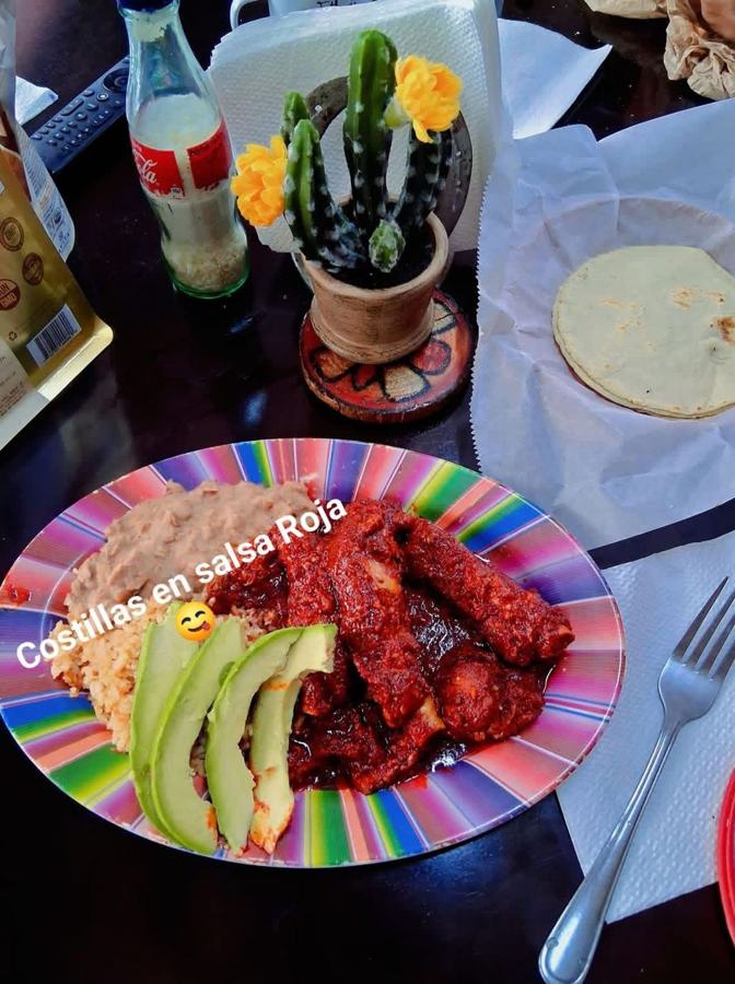 Pork ribs in red sauce with rice, beans, avocado and tortillas