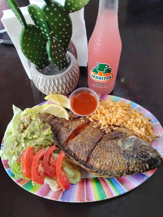 Whole fried fish with rice, guacamole, salad and a Jarritos soda